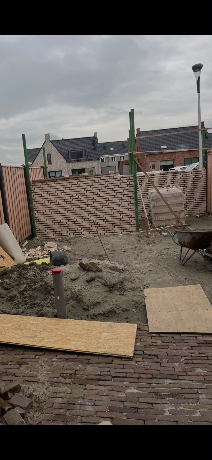 Bouwplaats overzicht tijdens de bouw van de schuur, met bakstenen pallet en gereedschap